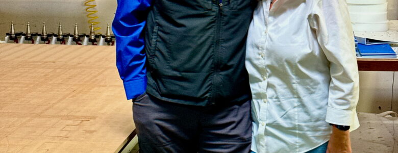 A Photo of Drew and Anita Schwartz standing next to a computer numerically controlled (CNC) router machine