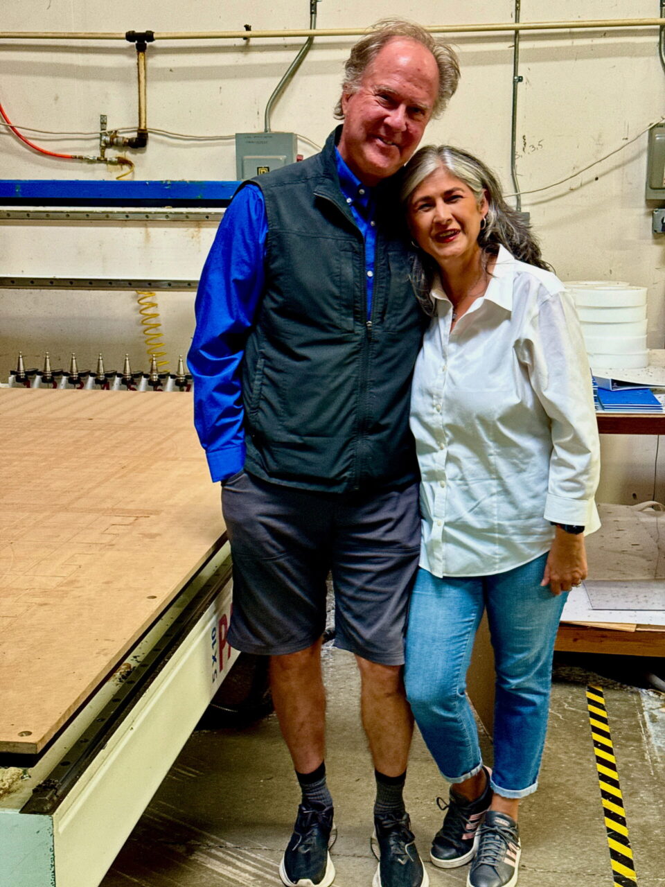 A Photo of Drew and Anita Schwartz standing next to a computer numerically controlled (CNC) router machine